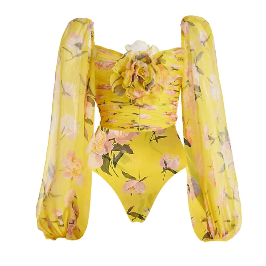 Maiô floral amarelo com mangas bufantes de tule e aplicação de flor em 3D no busto, moda praia feminina elegante.